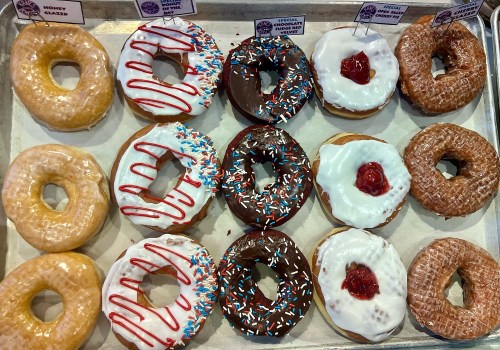 A tray of assorted donuts, including glazed, chocolate, and frosted varieties, decorated with sprinkles and toppings.