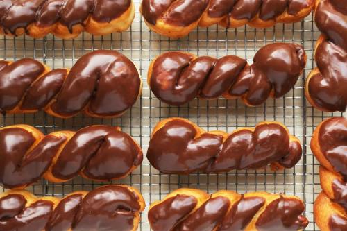 A close-up of chocolate-glazed twisted pastries arranged on a cooling rack.