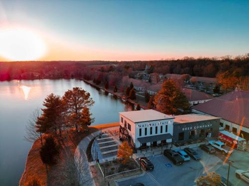 Aerial view of a lakeside area at sunset, featuring a brewery and surrounding trees.