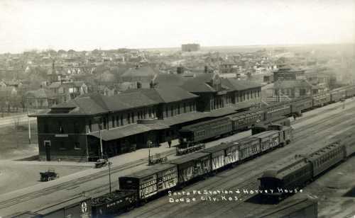 Historic black-and-white photo of Santa Fe Station and Harvey House in Dodge City, Kansas, with trains and buildings.