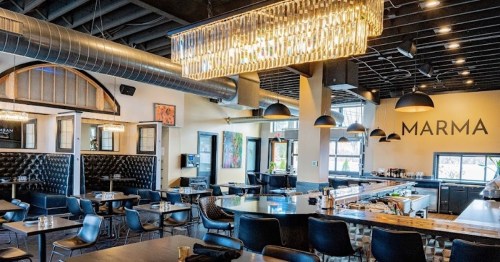 Modern restaurant interior with elegant lighting, black seating, and a stylish bar area.
