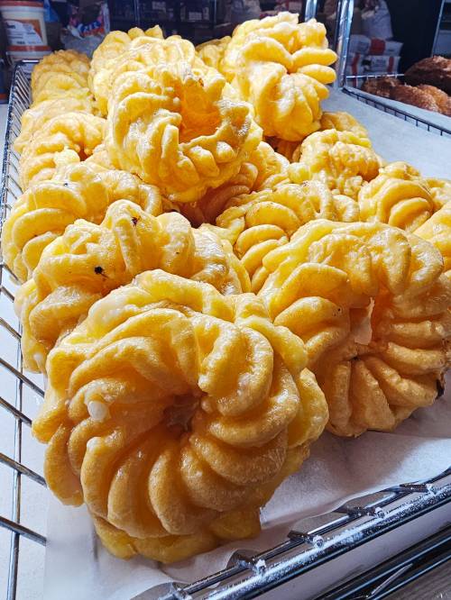 A close-up of golden, spiral-shaped pastries arranged in a basket, showcasing their fluffy texture.