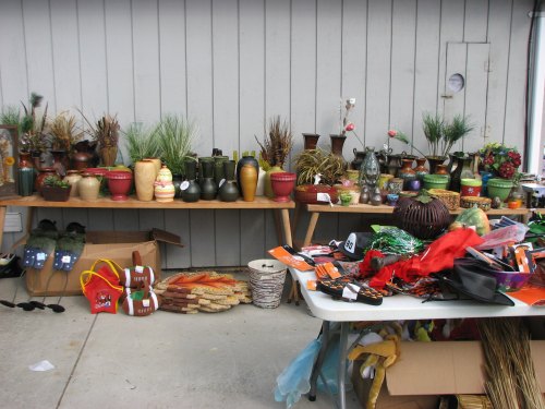 A display of various decorative pots and plants on a table, with additional items and decorations scattered nearby.