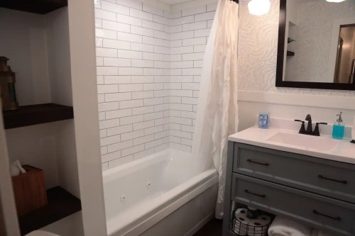 A modern bathroom featuring a white tiled shower, a bathtub, and a stylish vanity with a mirror.