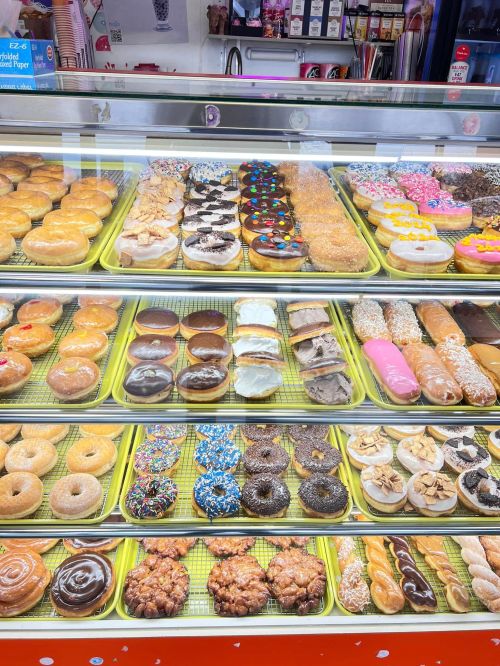 A display case filled with a variety of colorful donuts, including glazed, frosted, and sprinkled options.