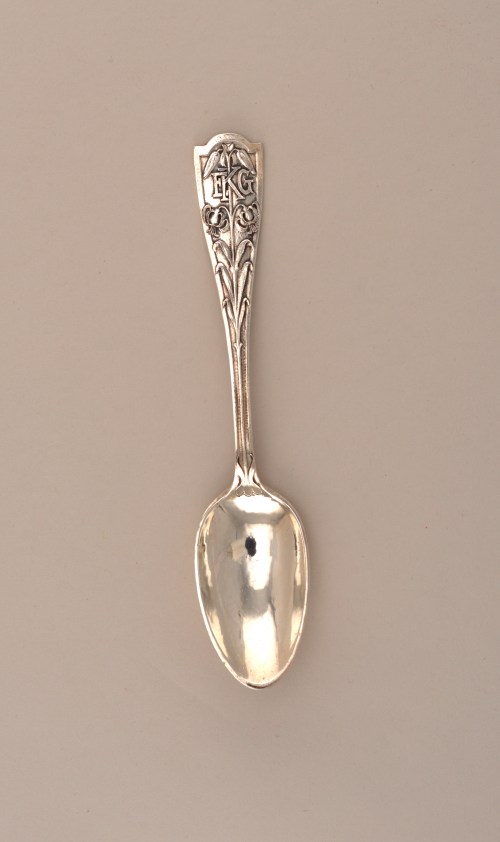 A decorative silver spoon with an ornate handle and a polished bowl, set against a neutral background.