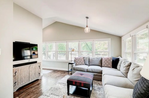 Cozy living room with a sectional sofa, TV, and large windows letting in natural light.