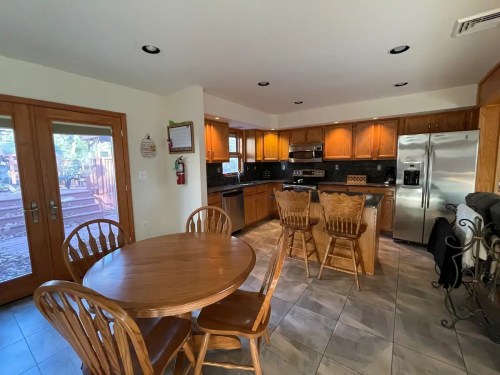Bright kitchen with wooden cabinets, stainless steel appliances, a round dining table, and sliding glass doors to the outside.