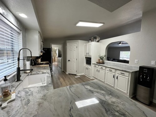 Modern kitchen with white cabinets, marble countertops, and stainless steel appliances, featuring a spacious layout.