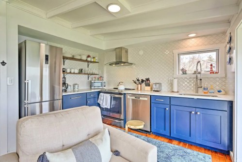 A modern kitchen with blue cabinets, stainless steel appliances, and a cozy seating area. Bright and inviting space.