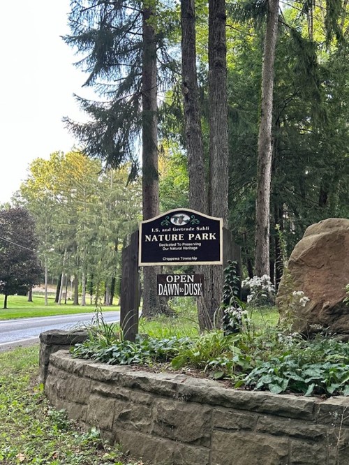 Sign for L.S. and Gertrude Sahl Nature Park, surrounded by trees, stating it's open from dawn to dusk.