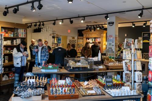 A cozy shop filled with games and gifts, featuring shelves of items and customers browsing around.