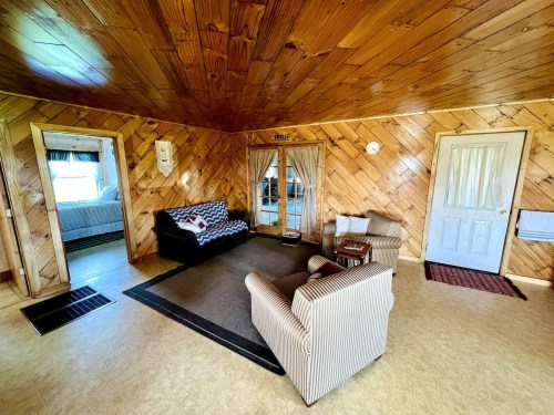 Cozy interior of a room with wooden walls, a patterned couch, and two doors leading to other spaces.