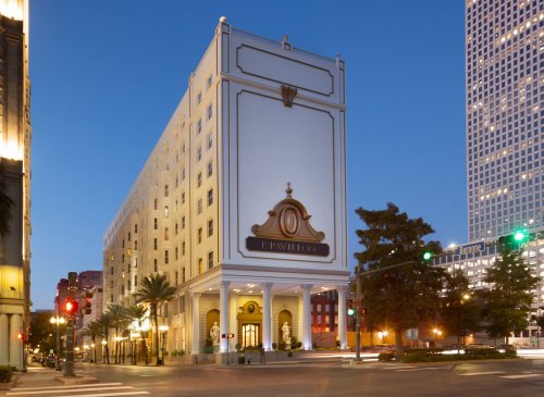 A tall hotel building at dusk, featuring a prominent sign and surrounding city lights.