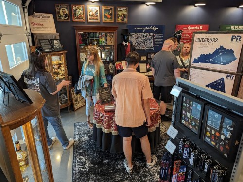 A group of people browsing a cozy shop filled with memorabilia, books, and local art on display.