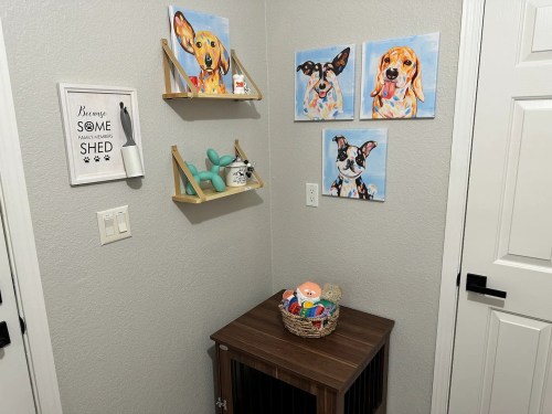 A cozy corner featuring dog-themed artwork, a basket of toys, and a sign about shedding on a gray wall.