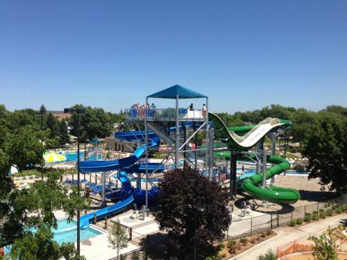 A water park featuring multiple slides, pools, and lush greenery under a clear blue sky.