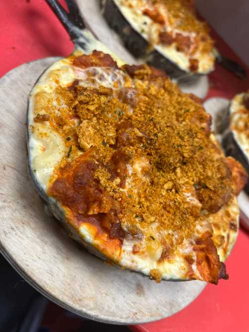 A close-up of a baked dish in a small skillet, topped with crispy breadcrumbs and melted cheese.