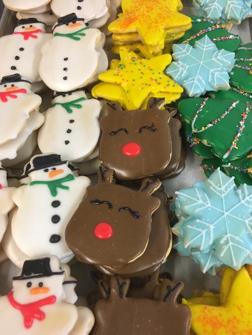 A variety of decorated holiday cookies, including snowmen, stars, reindeer, and snowflakes in vibrant colors.