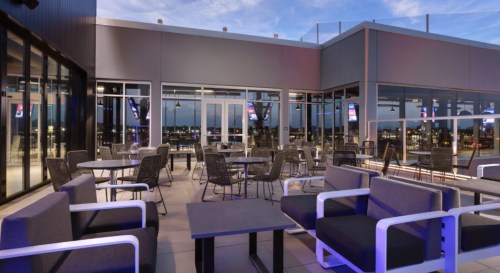 Rooftop patio with modern seating, tables, and city views under a twilight sky.