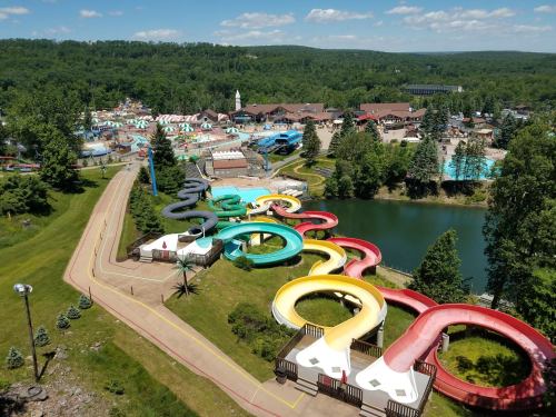 Aerial view of a water park featuring colorful slides, a lake, and lush green surroundings under a clear blue sky.