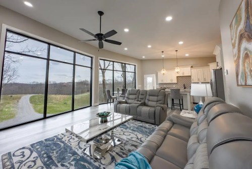Modern living room with large windows, a gray sofa, and a view of a scenic outdoor landscape.