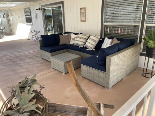 A cozy outdoor seating area with a navy blue sectional sofa and a small coffee table on a patio.