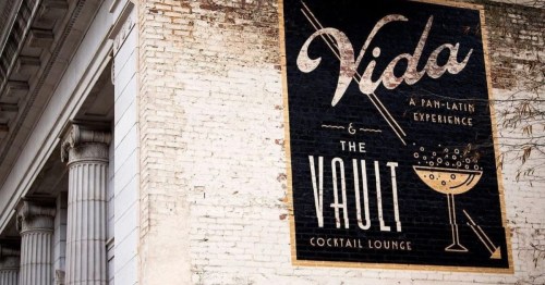 A mural featuring "Vida: A Pan-Latin Experience" and "The Vault Cocktail Lounge" on a brick wall.