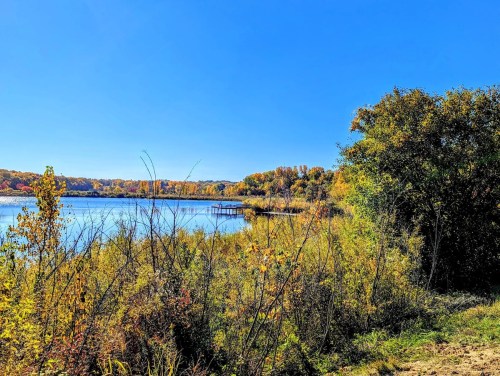 A serene lake surrounded by colorful autumn foliage under a clear blue sky.