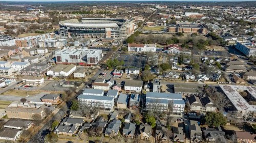 Aerial view of a cityscape featuring residential areas, commercial buildings, and a large stadium in the background.