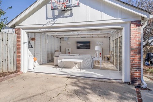 A spacious garage with a basketball hoop, white furniture, and a TV, featuring a clean, modern design.
