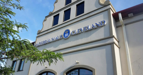 Exterior of Hofbräuhaus Cleveland building with a blue and gold sign against a clear sky.
