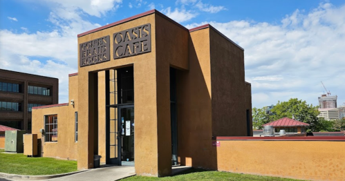 A modern orange building with "Oasis Café" and "Golden Era Records" signs, surrounded by green grass and blue sky.