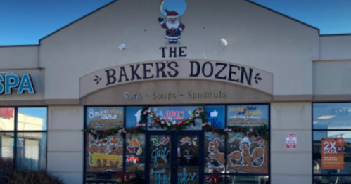 Exterior of "The Baker's Dozen" shop, decorated for the holidays with festive signage and a Santa figure.