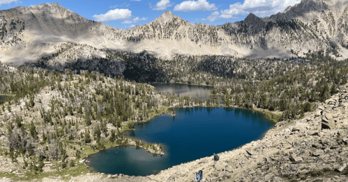 A scenic mountain landscape featuring blue lakes surrounded by rocky terrain and lush greenery under a clear sky.
