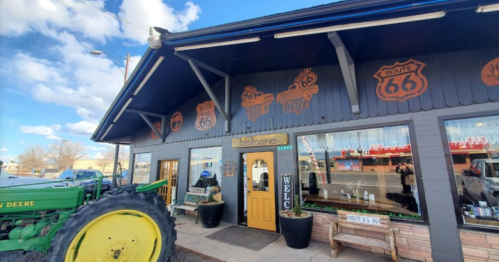A Route 66 café with a welcoming entrance, featuring vintage decor and a green tractor parked outside.