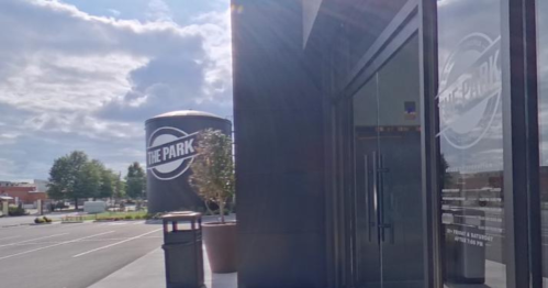 Exterior view of a building labeled "The Park," with a cloudy sky and parking lot in the background.