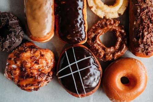 A variety of colorful donuts arranged on a surface, featuring chocolate, glazed, and topped options.