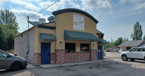 A small restaurant building with a sign reading "The Spot," featuring green awnings and a brick facade.
