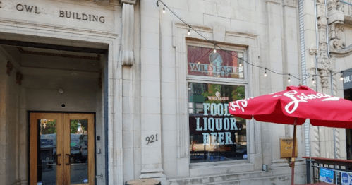 Exterior of the Owl Building featuring a sign for Wild Eagle and a red umbrella in front.