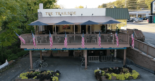 Aerial view of The Trailside restaurant with outdoor seating, umbrellas, and American flags along the balcony.