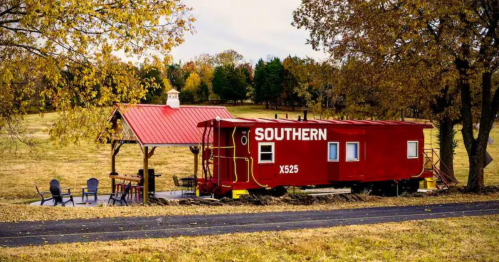 A red caboose labeled "SOUTHERN" sits beside a gazebo in a grassy area with trees in the background.