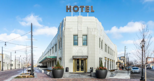 Exterior view of the Art Deco-style Rottlerman Hotel, featuring a prominent "HOTEL" sign and landscaped planters.