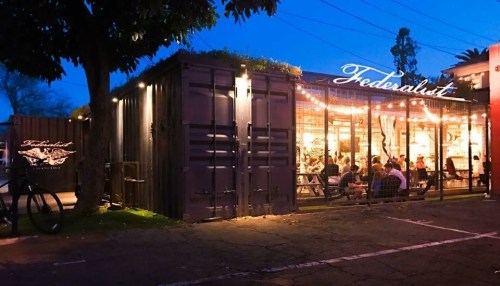 A cozy restaurant named "Federalist" with outdoor seating, illuminated by string lights at dusk.