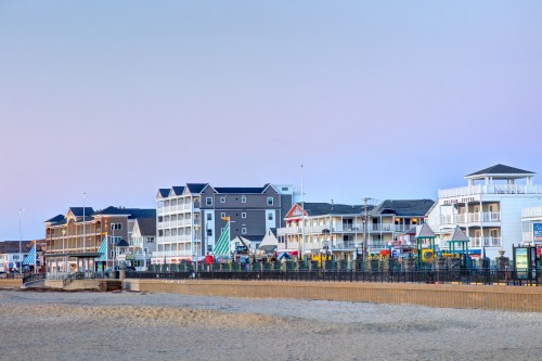 Coastal scene featuring colorful beach houses and a sandy shore under a pastel sky.