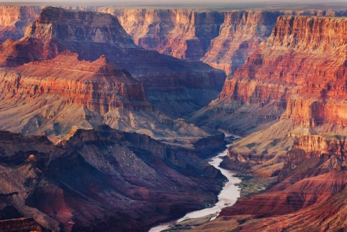 A stunning view of the Grand Canyon, showcasing layered red rock formations and a winding river below.