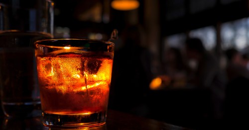 A glowing amber cocktail in a dark, intimate setting at the Blind Lion, a hidden South Dakota speakeasy.