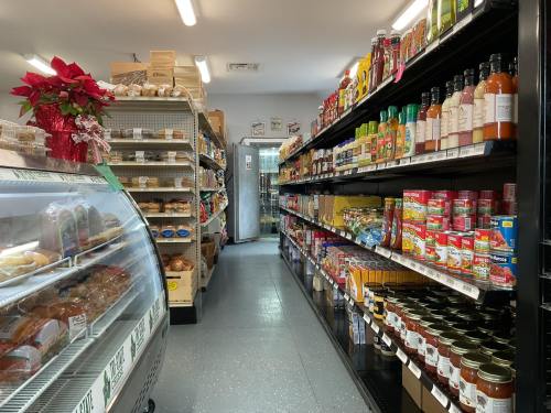 A grocery store aisle with shelves stocked with various food items and a display case on the left.