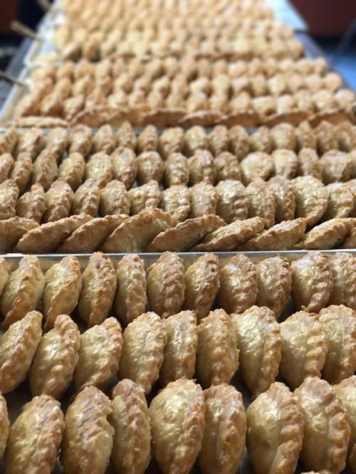 A close-up view of rows of golden-brown pastries arranged neatly on a tray.