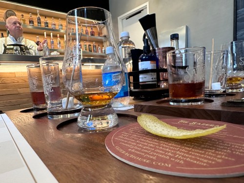 A bar scene with empty glasses, a lemon peel, and a bartender in the background.